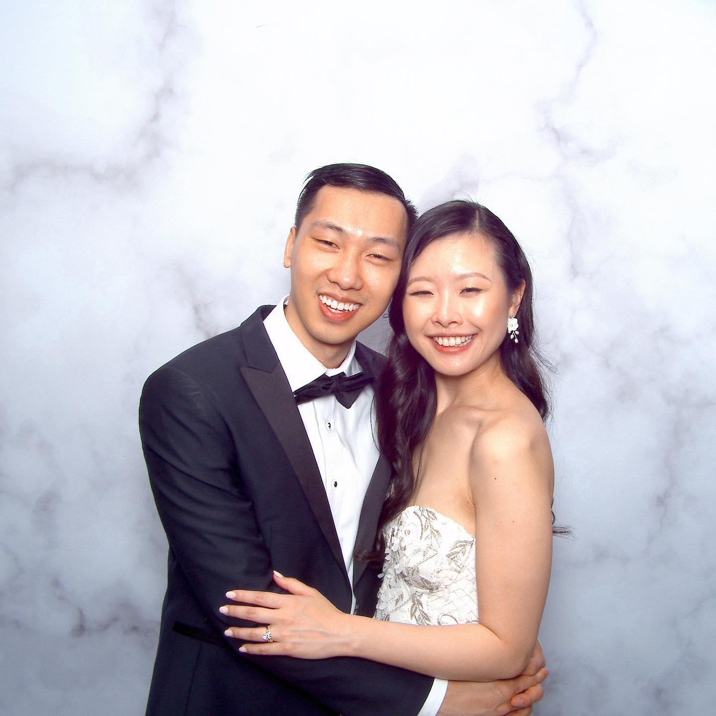 A couple smiling and posing in front of our modern photo booth rental